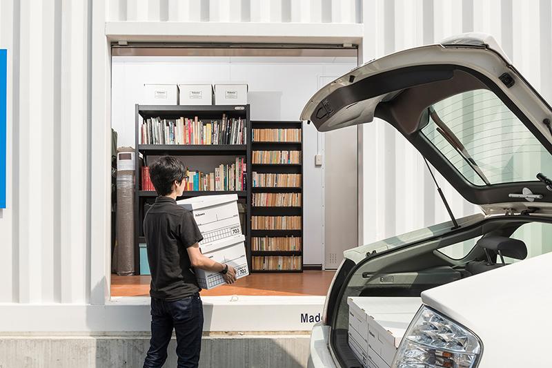 車からトランクルームに荷物を運ぶ人